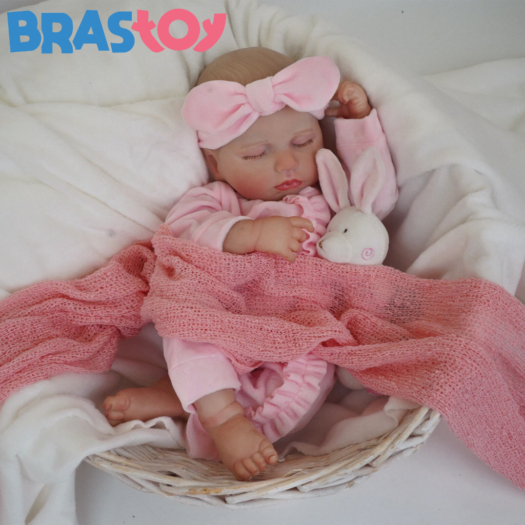 Brastoy Bebê Reborn Boneca Silicone 48cm Menina Pode dar Banho 1 Boneca Bebê Reborn Brastoy de Silicone 48cm Menina, com cabelos loiros, olhos azuis e expressão realista, vestindo uma roupa de bebê rosa e com acessórios como chupeta e mamadeira, pronta para brincar ou ser cuidada, inclusive no banho.